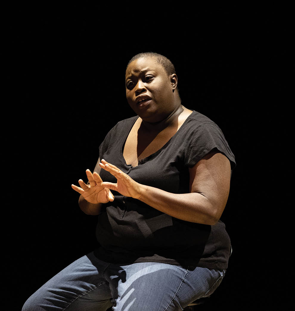 photo of black artist speaking and sitting on stool on stage